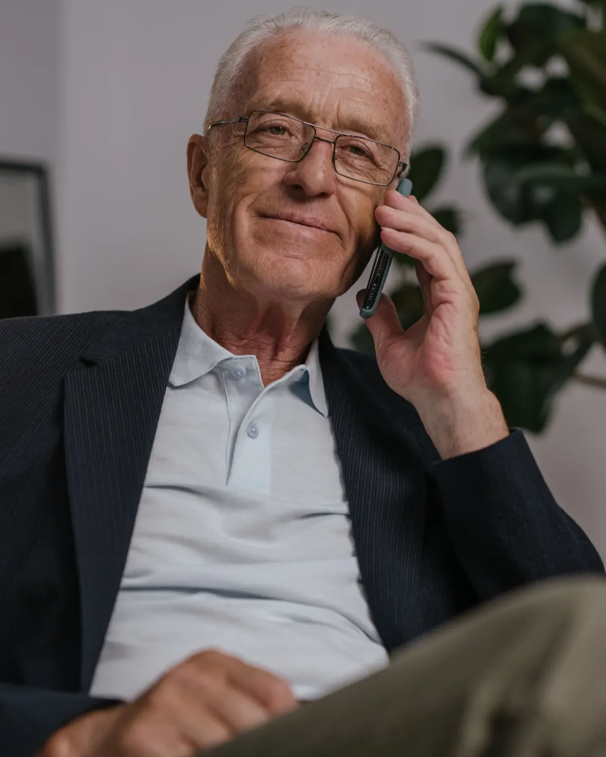 An older man in glasses smiling gently as he listens on the phone