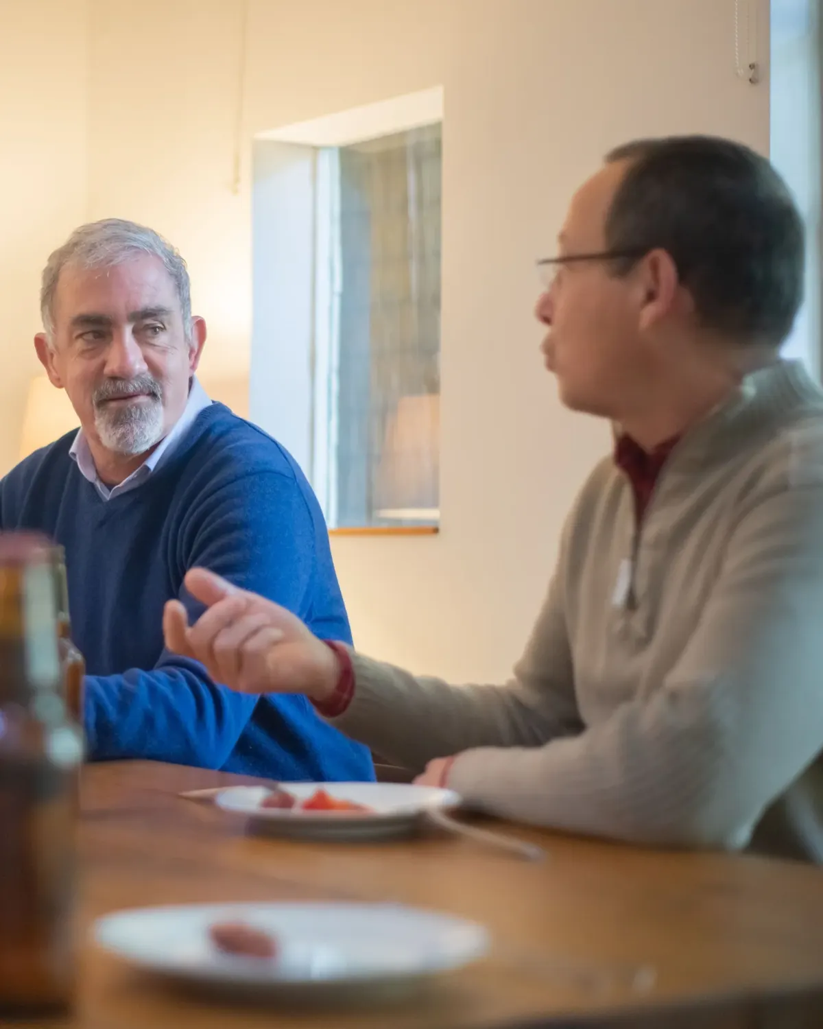 Two men talking across a table during a shared meal