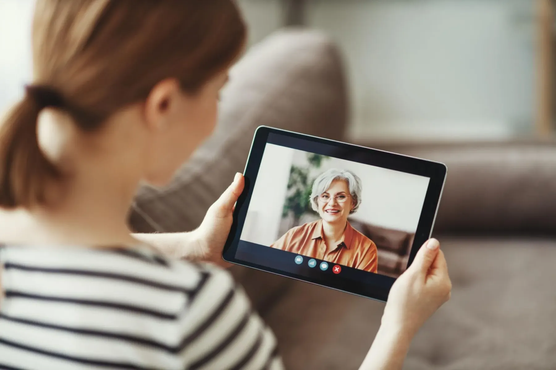 A woman holding a tablet on a video call with a smiling older woman