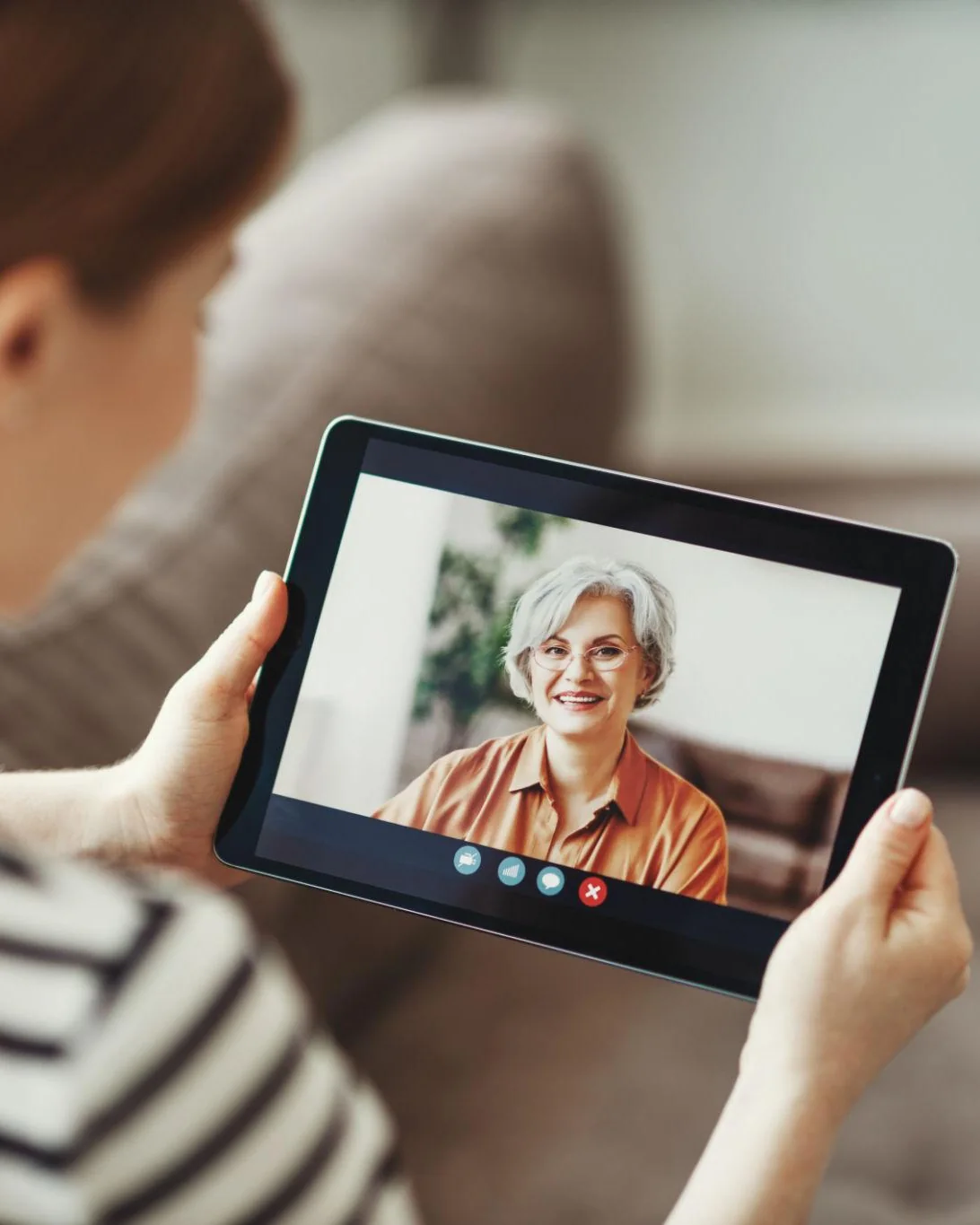 A woman holding a tablet on a video call with a smiling older woman