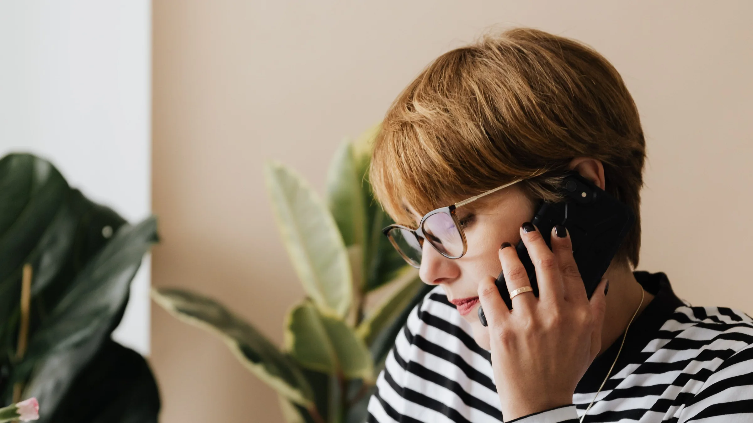 A woman in glasses concentrating on a phone call